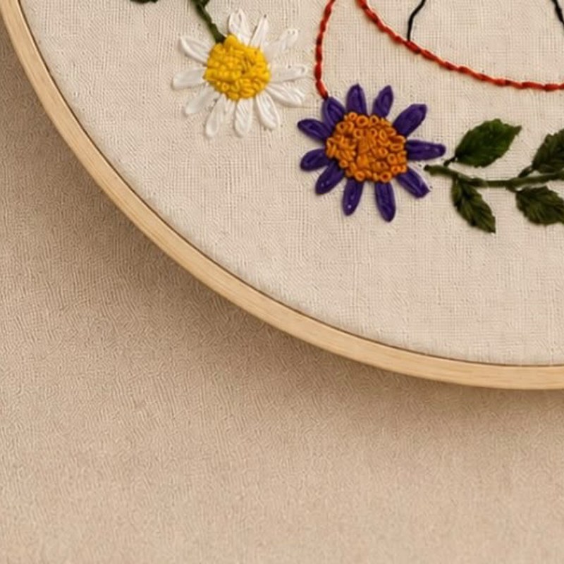 Detalhe de margarida e flor roxa bordadas em ponto cheio